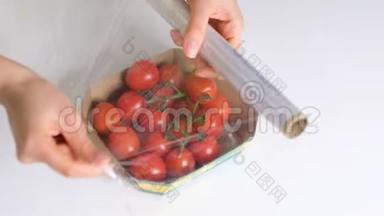 女人用食物胶片在白色桌子上储存食物。 包装产品用透明聚乙烯食品膜辊